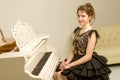 A teenage girl is playing on a white grand piano. Royalty Free Stock Photo