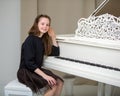 A teenage girl is playing on a white grand piano. Royalty Free Stock Photo