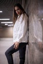 The teenage girl pressed her back against the wall. Brunette in the underpass at night, reflection from the wall. Royalty Free Stock Photo