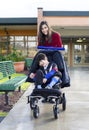 Teenage girl pushing disabled boy in wheelchair