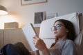 Teenage girl reading book at home while sitting on sofa Royalty Free Stock Photo