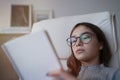 Teenage girl reading book at home while sitting on sofa Royalty Free Stock Photo