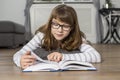 Teenage girl reading book while lying on floor at home Royalty Free Stock Photo