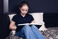 A teenage girl is reading a book while sitting on the bed. A child reads the Bible. Prayer Royalty Free Stock Photo