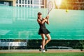 Teenage girl returning the ball, playing tennis on an outdoor tennis court