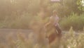 Teenage girl rides on a brown horse on horse farm.