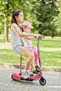 Teenage girl rides scooter, holding little girl on Royalty Free Stock Photo