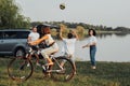 Teenage Girl Riding Bicycle While Mother and Father Playing Volleyball with Her Brother Outdoors by the Lake, Happy Four Royalty Free Stock Photo