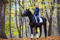 Teenage girl riding horse in autumn park Royalty Free Stock Photo