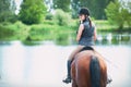 Teenage girl riding horseback to the river at early morning Royalty Free Stock Photo