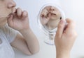 Teenage girl with mirror reflecting half of her face,inserts orthodontic metal braces for teeth alignment into her mouth