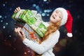 Teenage girl in a Santa hat holds gifts in her hands