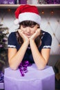 A teenage girl in a Santa hat is sad over a big Christmas present