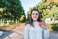 Teenage girl schoolgirl, teenager white sweater autumn in city background trees road, warm sweater, in hands of toy