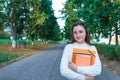 Teenage girl schoolgirl, teenager white sweater summer city, warm sweater, hands notebooks books and folders, smiling