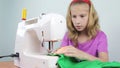 A teenage girl sews braid to the edge of a piece of cloth