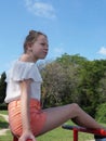 Teenage girl in shorts sits on bars in the park