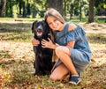 Teenage girl sit hugging a black dog in park Royalty Free Stock Photo