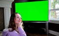 teenage girl sits admiringly in front of a big chroma key tv monitor ad enthusiastically points finger laughs thumbs up