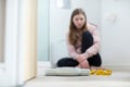 Unhappy Teenage Girl Sitting In Bathroom Looking At Scales And Tape Measure Royalty Free Stock Photo