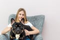 Teenage girl sitting in a chair at home with her French Bulldog dog in her arms