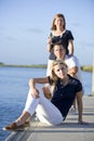 Teenage girl sitting on dock by water with parents