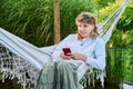 Teenage girl sitting in hammock using smartphone for leisure study communication Royalty Free Stock Photo