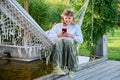 Teenage girl sitting in hammock using smartphone for leisure study communication Royalty Free Stock Photo