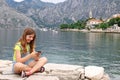 Teenage girl sitting near sea and having fun with smart ph Royalty Free Stock Photo