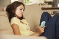 Teenage Girl Sitting On Sofa At Home Texting On Mobile Phone Royalty Free Stock Photo