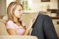 Teenage Girl Sitting On Sofa At Home Using Tablet Computer Royalty Free Stock Photo