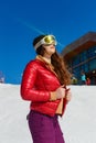 A teenage girl in ski glasses looks at the sun on a mountain slope in winter