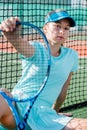 Emotionless teenage girl sitting on tennis court, holding racket close to camera Royalty Free Stock Photo