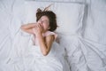 Young woman sleeping well in bed hugging soft white pillow. Teenage girl resting. good night sleep concept. Girl wearing a pajama Royalty Free Stock Photo