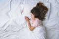 Young woman sleeping well in bed hugging soft white pillow. Teenage girl resting. good night sleep concept. Girl wearing a pajama Royalty Free Stock Photo