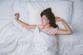 Young woman sleeping well in bed hugging soft white pillow. Teenage girl resting. good night sleep concept. Girl wearing a pajama Royalty Free Stock Photo