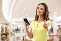 Teenage girl with smartphone showing thumbs up