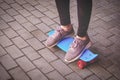 Teenage Girl In Spurt Shoes is standing on small pennyboard skateboard on footpath Royalty Free Stock Photo