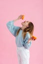 Teenage girl squeezing orange juice in mouth isolated on pink Royalty Free Stock Photo