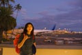 Teenage girl standing at Hawaiian airport making shaka sign