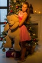 Teenage Girl Standing near Christmas Tree Holding Big Teddy Bear Royalty Free Stock Photo
