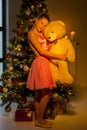 Teenage Girl Standing near Christmas Tree Holding Big Teddy Bear Royalty Free Stock Photo