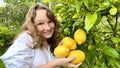 a teenage girl is standing near a lemon tree she is holding a lemon in her hands she is sniffing it she is going to make Royalty Free Stock Photo