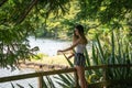 Teenage girl in shade stands by railing looking at lake