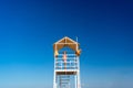 Teenage girl stands on lifeguard tower on beach against cloudless sky