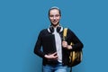 Teenage girl student with backpack holding laptop on blue background Royalty Free Stock Photo