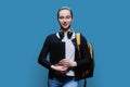 Teenage girl student with backpack holding laptop on blue background Royalty Free Stock Photo