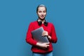 Teenage girl student in headphones with laptop in hands on blue background Royalty Free Stock Photo