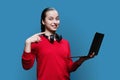 Teenage girl student in headphones using laptop on blue background Royalty Free Stock Photo