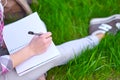 Teenage girl student writing in notebook in park. Preparation for exams at college or university Royalty Free Stock Photo